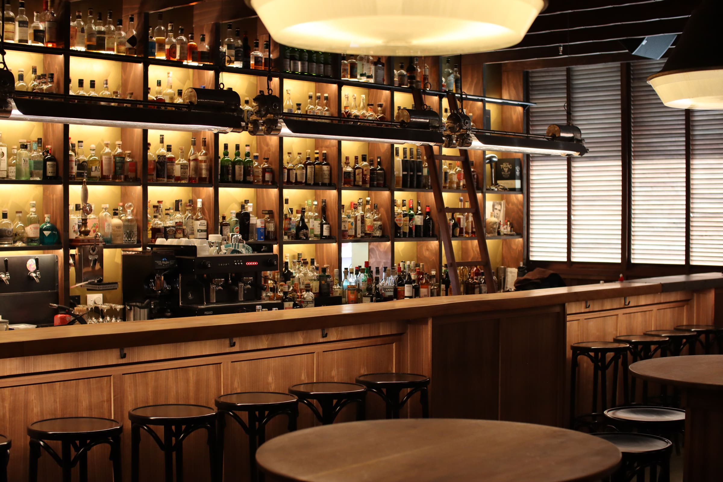Timber-lined bar with backlit spirit shelving and pendant lighting