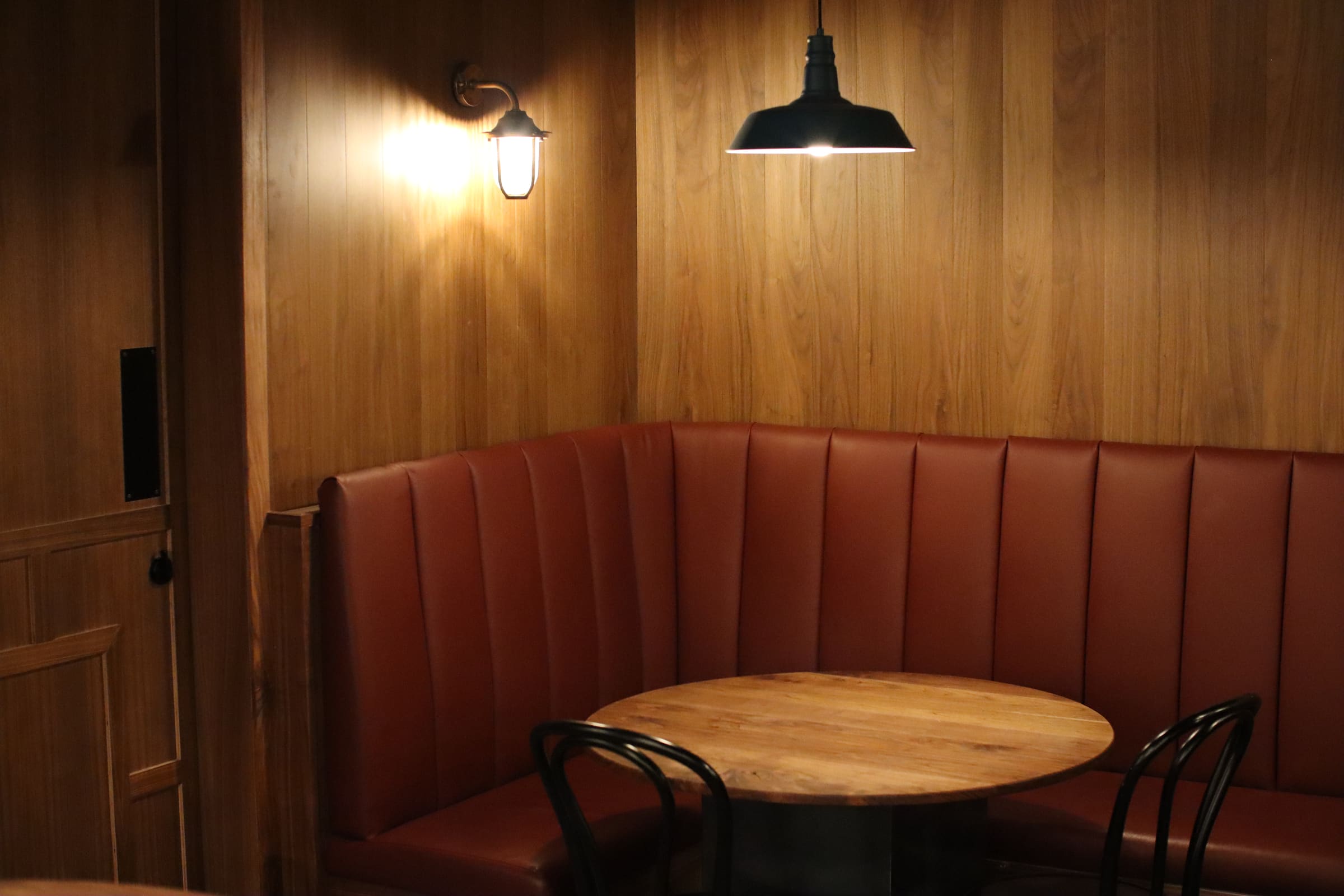 Curved leather banquette seating in a timber-panelled dining nook